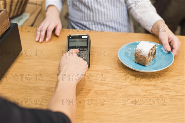 Close up customer using pin machine pay bill delicious cake slice