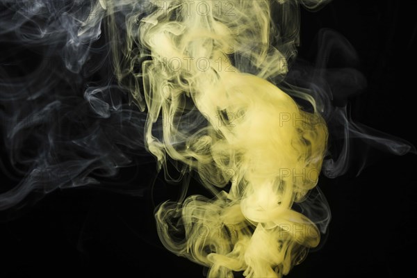 Close up yellow smoke against black background