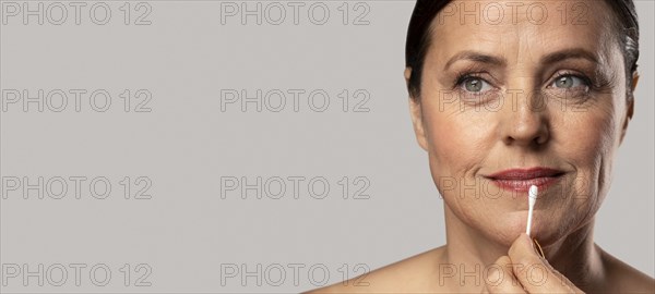 Elder woman removing lipstick with cotton swab