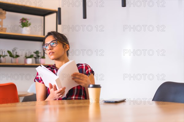 Woman reading a book sitting on a table with a coffee