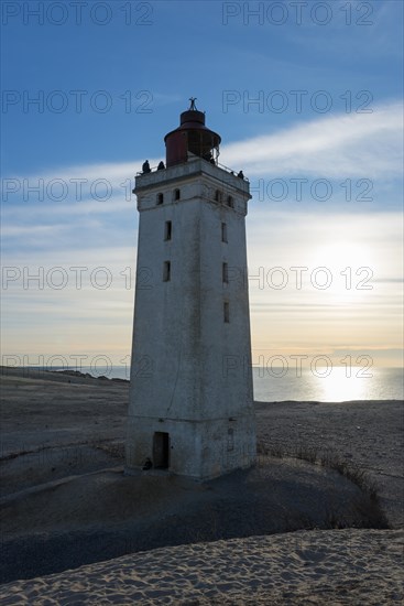 Lighthouse and dune at sunset