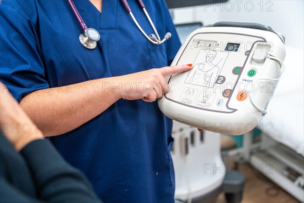 Close-up of an unrecognizable cardiologist explaining how a small defibrillator works