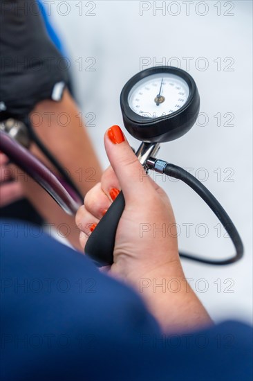 Doctor measuring the blood pressure of a woman sitting on a stretcher in a clinic room