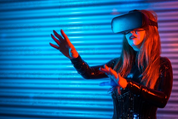 Amazed futuristic woman using Virtual reality goggles in an urban night space with neon lights