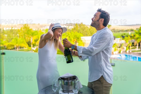 Happy moments of a couple opening a champagne bottle in an hotel