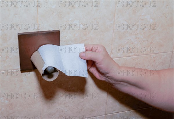A woman's hand tries to reach for toilet paper but the roll has run out