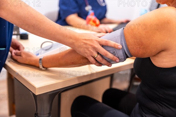 Nurse measuring the blood pressure of a mature patient during a cardiology visit