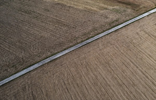 Drone view of a country road between harvested and green fields