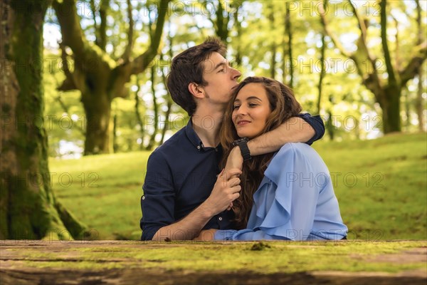 Frontal horizontal photo of tender scene of lovers embracing in a forest