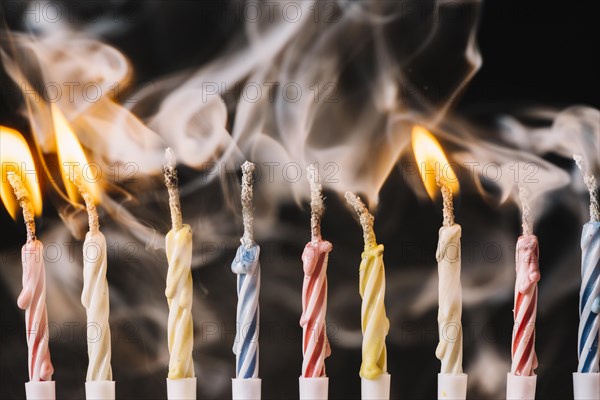 Burning extinguished candle against black background