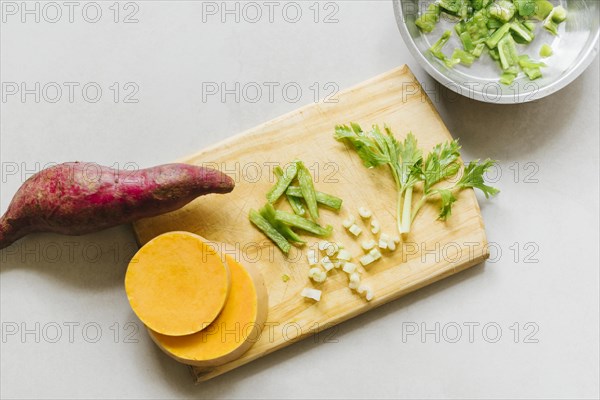 Elevated view sweet potato sliced pumpkin celery cutting board