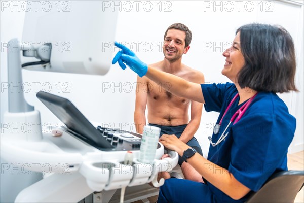 Cardiologist explaining the results on the screen of a echocardiogram to a patient sitting on stretcher in an hospital room