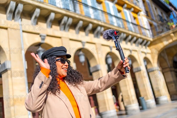 Blogger waving at camera during a life video visiting a city in a sunny day of winter