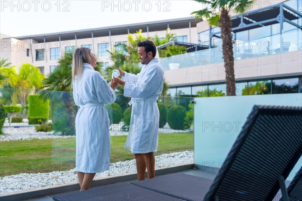 Couple hydrating with water next to a pool in a luxury hotel