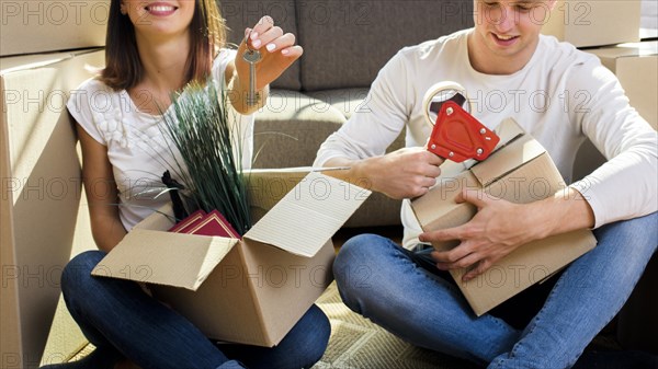 Joyfull couple packing things cardboard boxes