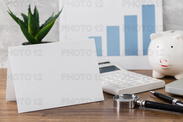 Front view desk with blank paper piggy bank