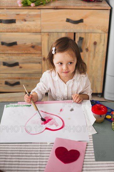 Little girl painting heart paper