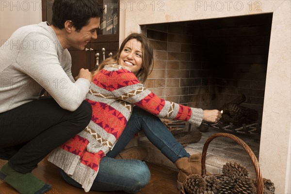 Man looking young woman ignite big match fireplace