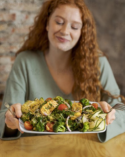 Medium shot woman holding plate with food