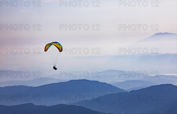 Paragliders high above the mountains with a view of the Klagenfurt basin and the Karawanken