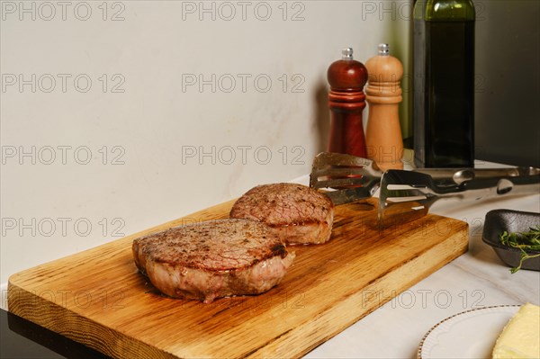 Two pieces of fried beef steak rest on wooden cutting board