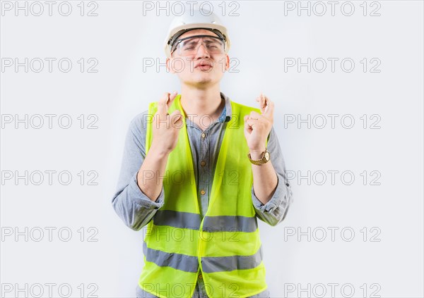 Portrait of young engineer making a wish. Handsome engineer crossing fingers making a wish