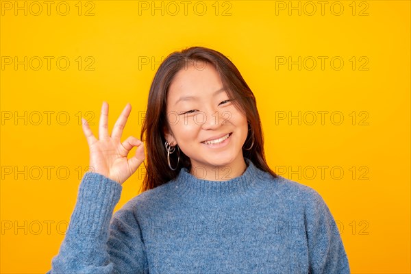 Asian woman acting cool and wonderful looking at camera on a yellow background