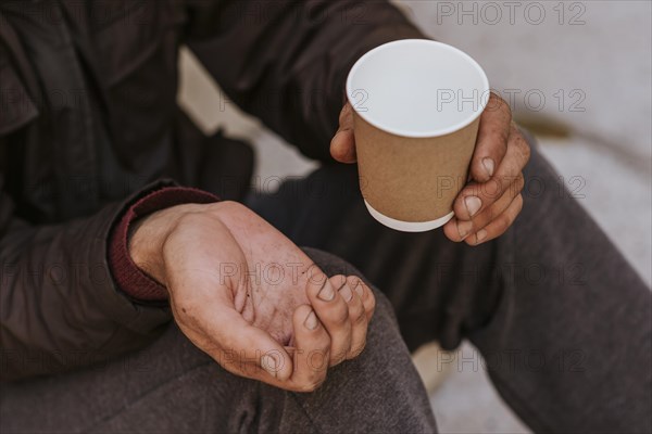 Homeless man holding hand out help empty cup