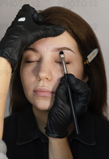 Front view woman getting eyebrow treatment from specialist