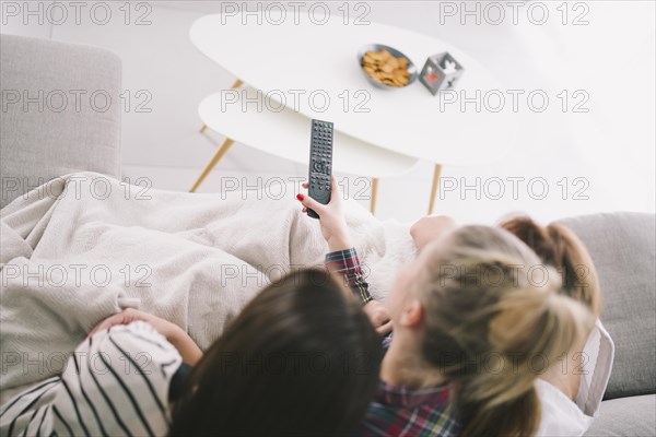 Girlfriends watching tv cuddling sofa