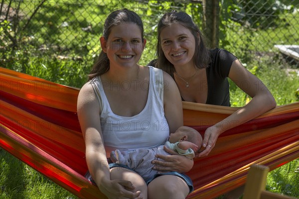 Young mother with baby in a hammock in the garden