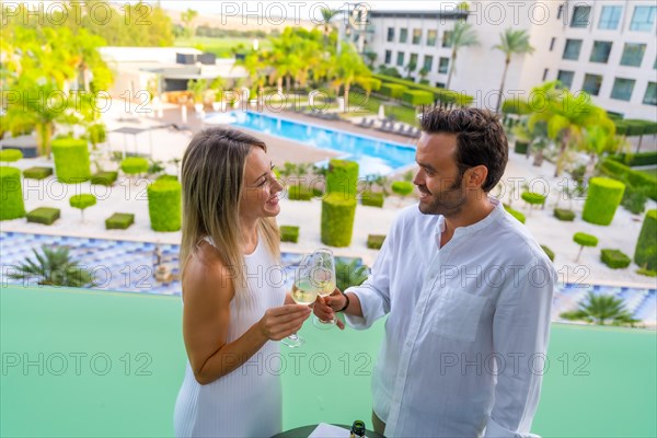 Newlywed couple toasting with champagne standing on the terrace of a luxury hotel