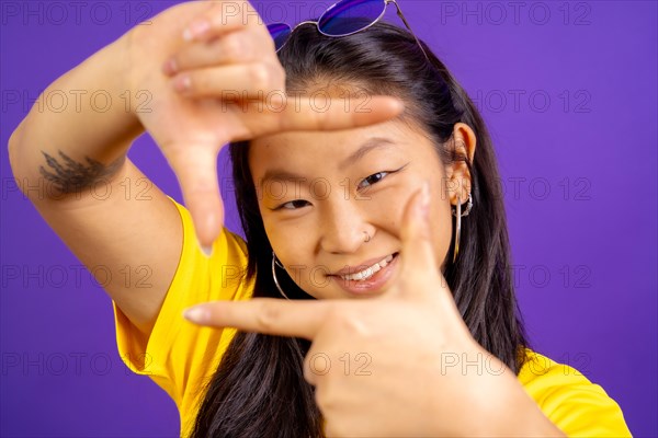 Studio photo with purple background of a chinese woman smiling and framing with hands