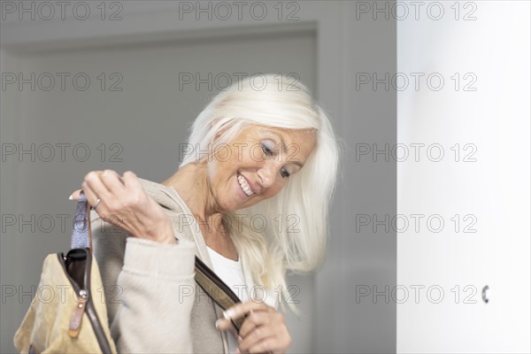 Elderly woman with long hair and bag leaves home in a hurry