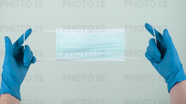 Front view hands with surgical gloves holding medical mask