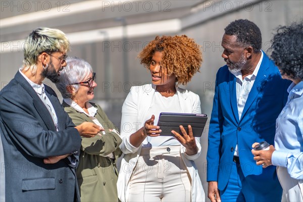 African businesswoman using tablet while explaining a project to colleagues in an outdoors business meeting