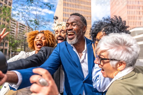 Side view portrait of a happy mature african businessman taking a selfie with colleagues outdoors