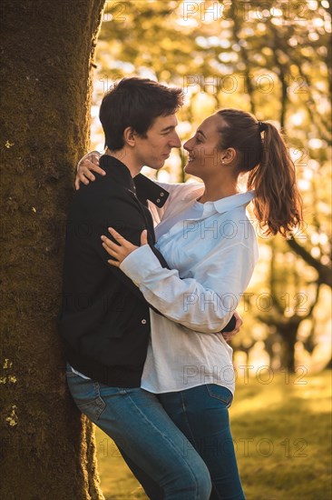 Romantic scene of a couple about to kiss leaning on a tree