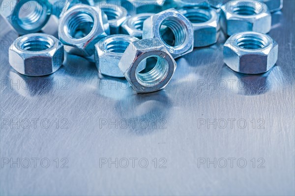 Large set of stainless steel nuts on metallic background Construction concept