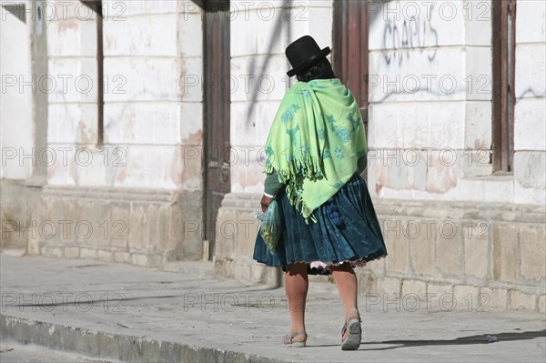 Woman in traditional dress wearing bowler hat and skirt at Uyuni