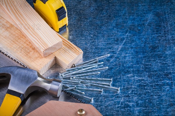 Composition of metal nails Hammer Wooden bricks Hacksaw Tape measure on scratched metal surface Construction concept