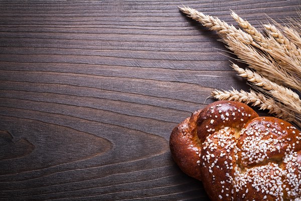 Copy space image of sweet roll wheat rye ears on wooden background food and drink concept