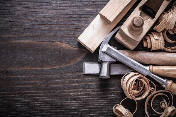 Planner claw hammer fixed chisel wooden bricks and curled shavings on vintage wooden board Building concept