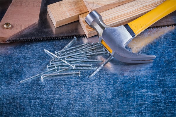 Close up image of metal nails hammer wooden bricks hacksaw on scratched metallic surface construction concept