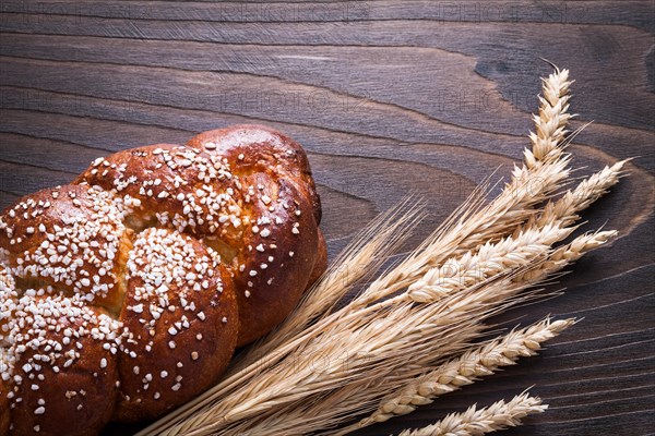 Long loaf of wheat rye ears on wooden background food and drink concept