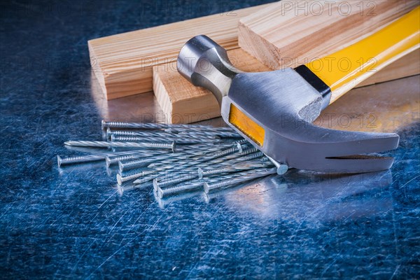 Metal nails Claw hammer and wooden bolts on scratched metallic background Construction concept