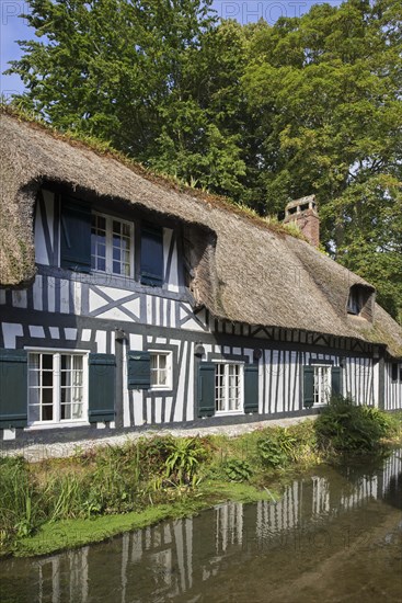 Timber-framed house with thatched roof along the river Veules