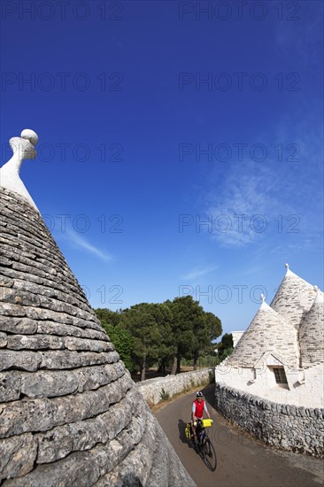 Cyclist between trulli near Noci