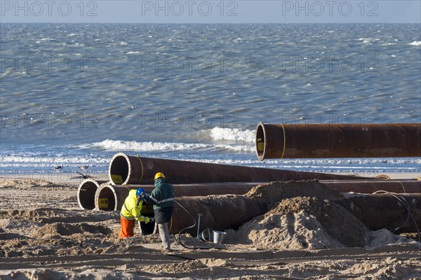 Dredging workers connecting pipes of pipeline during sand replenishment
