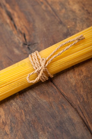 Italian pasta spaghetti tied with a rope on a rustic table